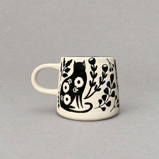 Impish Greetings Catbloom stoneware mug with black cat and floral imprint on a cream background
