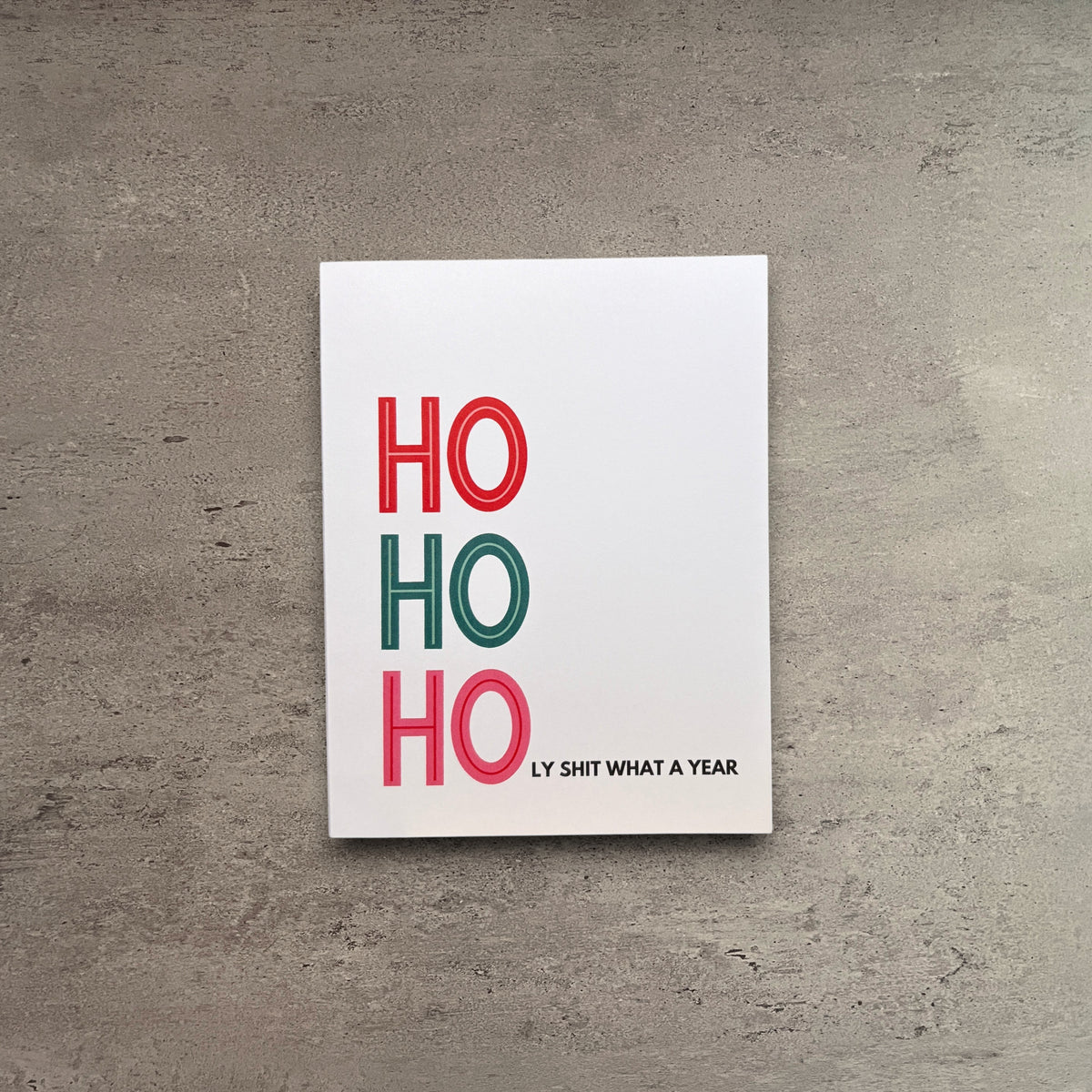 Ho Ho Holy Shit What A Year Christmas card on white cardstock with a kraft brown envelope.