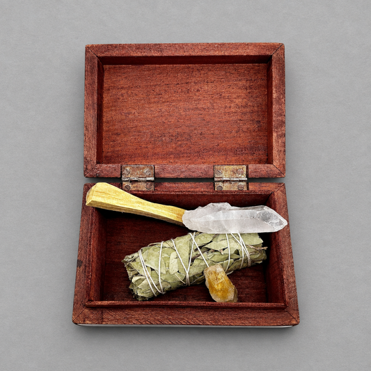 Impish Greetings hand-carved mango wood box containing a sage smudge stick, palo santo, and crystals.