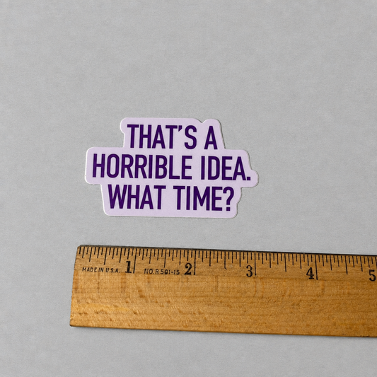 Impish Greetings Horrible Idea vinyl sticker with purple text on a white background next to a wooden ruler.