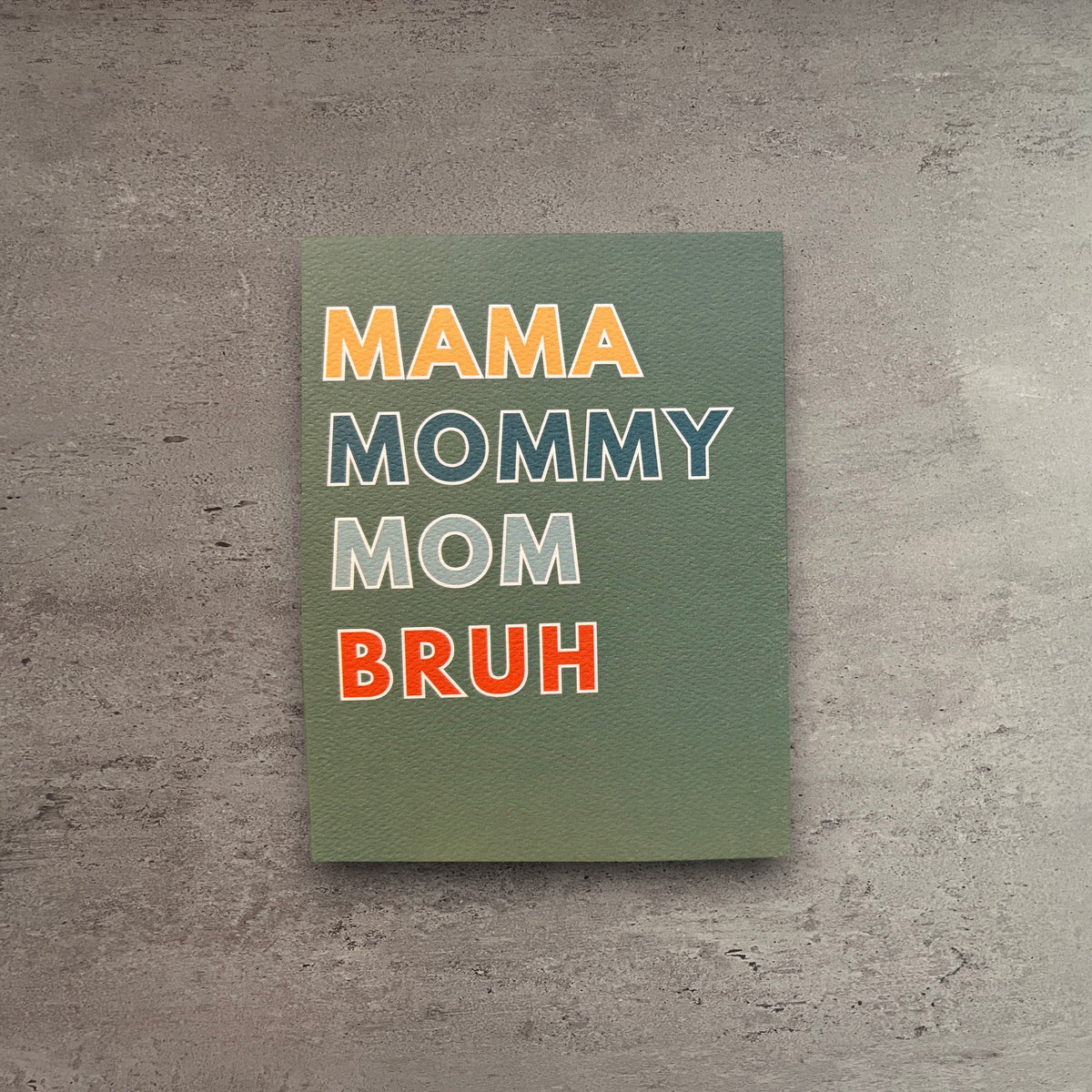 Impish Greetings Mama Mommy Mom Bruh greeting card on textured green paper with a kraft envelope on a wooden table.