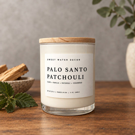 Impish Greetings Palo Santo Patchouli 11 oz soy candle in a glass jar with a wooden lid on a rustic wooden table.