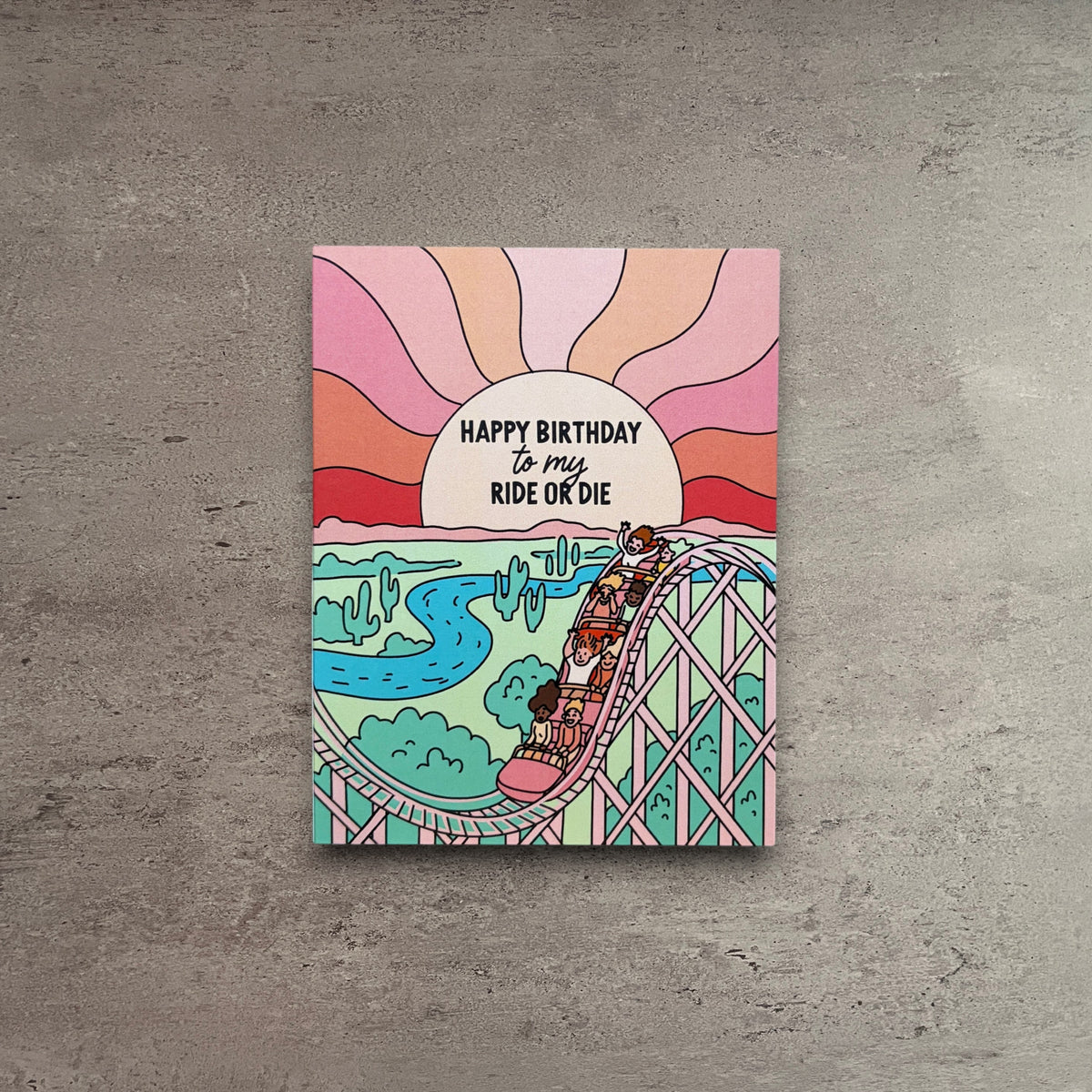 Impish Greetings Ride or Die birthday card featuring a colorful roller coaster illustration with a sunset background.