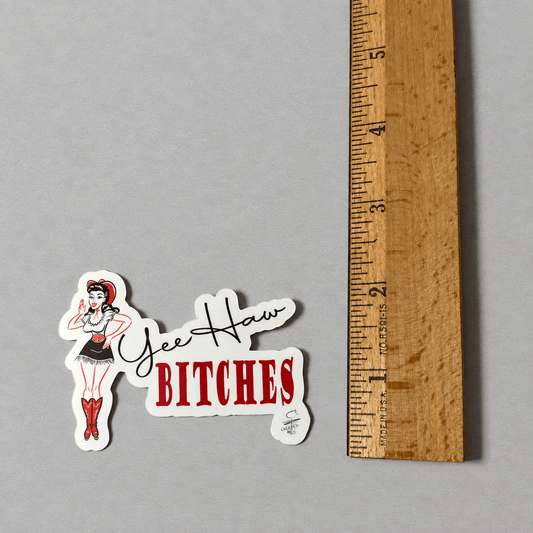 Impish Greetings Yee Haw Bitches vinyl sticker featuring a pin-up cowgirl illustration next to a wooden ruler