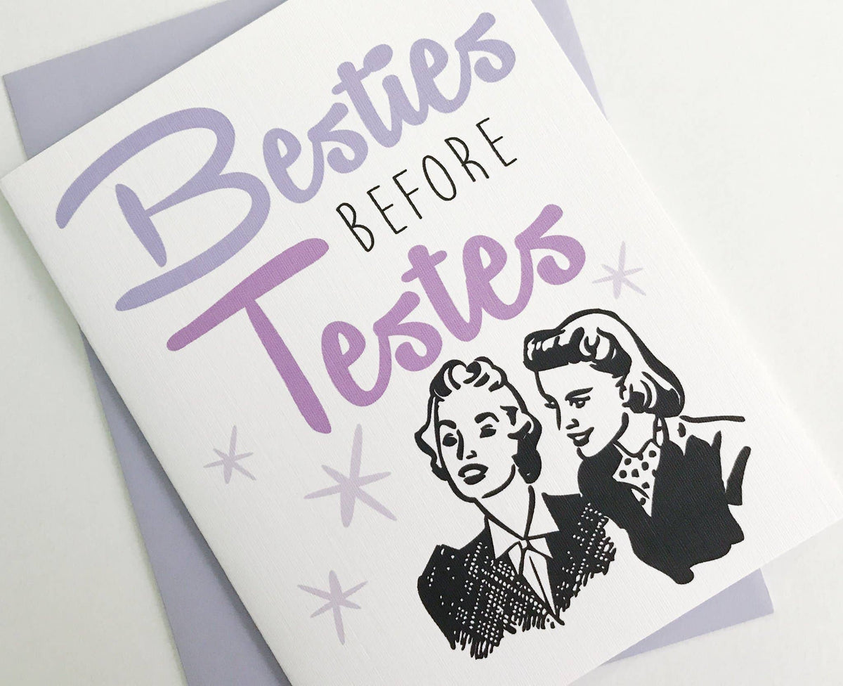 Greeting card with 'Besties Before Testes' text and vintage-style illustration of two women on a light gray background.