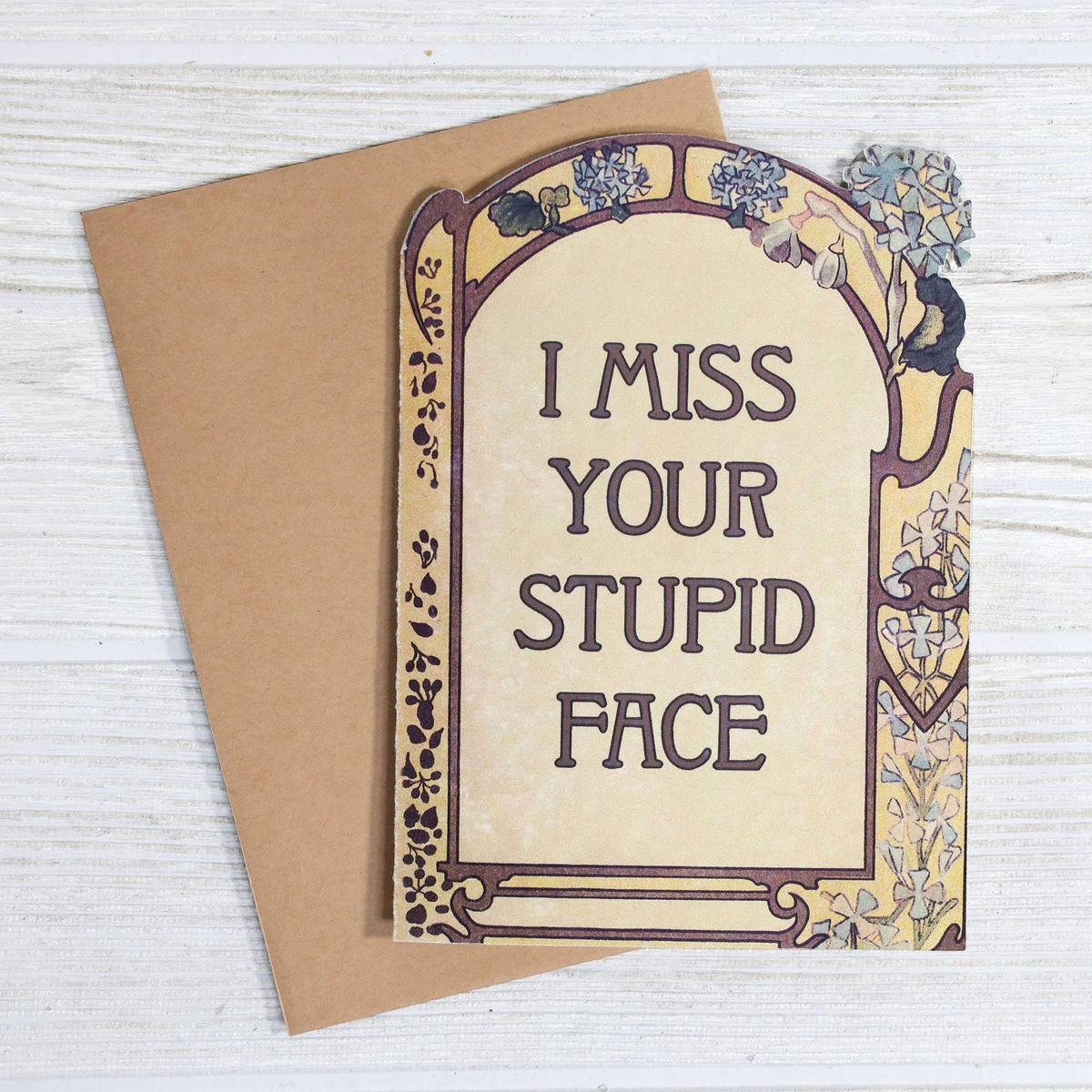 Impish Greetings I Miss Your Stupid Face greeting card with vintage floral border and matching kraft paper envelope.