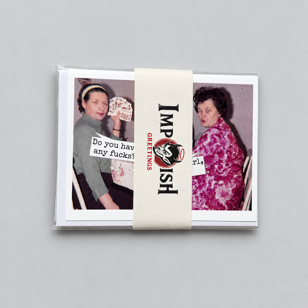 A stack of printed cards or stickers tied with a cream paper band labeled 'Imp Shit' and 'Censored,' placed on a textured gray surface. The visible card designs show two women in vintage-style photos with text including 'Do you say way fuckin?'.