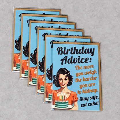Five matching vintage-style birthday cards are arranged in a fan shape on a textured gray surface. The cards feature a retro illustration of a woman with black hair and an orange dress, with the text 'Birthday Advice: The more you weigh the harder you are to kidnap.