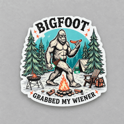 A die-cut vinyl sticker featuring a cartoon Bigfoot holding a hot dog in a camping scene with the text 'BIGFOOT GRABBED MY WIENER', shown on a neutral gray background.
