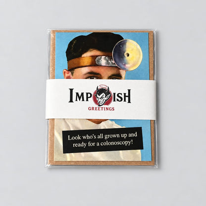 A sealed card set from Impish Greetings featuring a humorous card with a colonoscopy joke and a photo of a man wearing a colonoscope, placed on a gray textured surface.