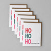 Five stacked white greeting cards with brown edges, featuring the text 'HO HO HO' in red and green, and the phrase 'LY SHT WHAT A YEAR' on a textured gray background.