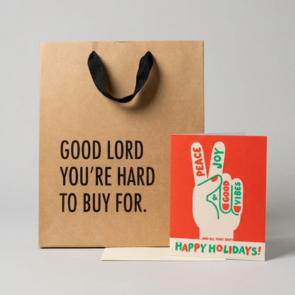 Kraft gift bag and holiday greeting card on a muted light grey background