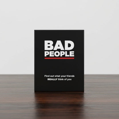 Impish Greetings Bad People adult party card game box in black with white text on a wooden table