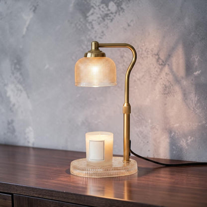 Impish Greetings candle lamp warmer with a brass finish and textured glass shade heating a white candle on a desk
