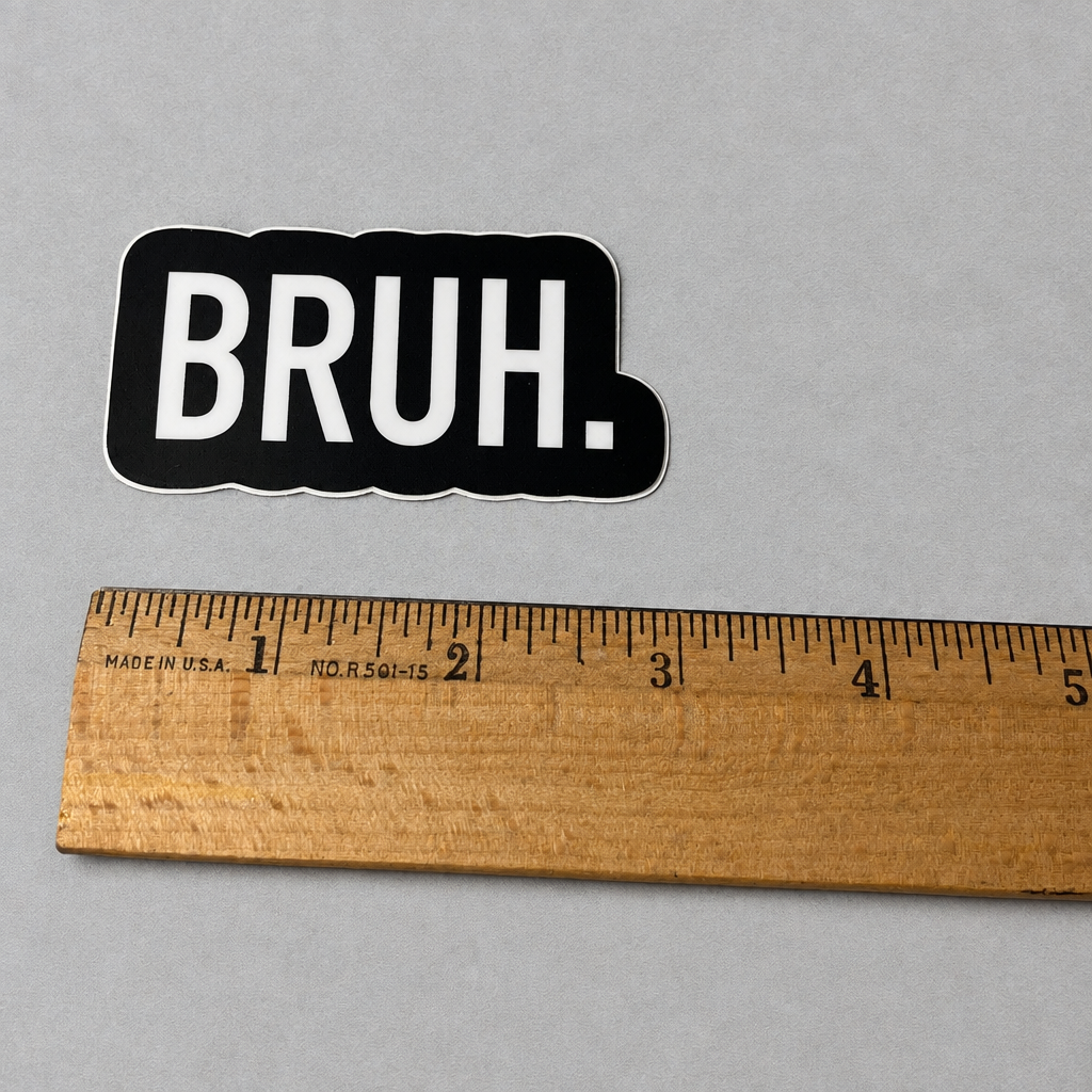 Impish Greetings Bruh vinyl sticker with white text on a black background next to a wooden ruler for scale.