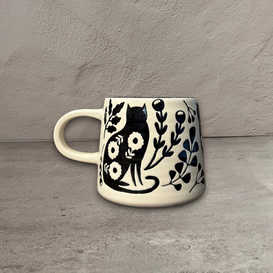 Impish Greetings Catbloom stoneware mug featuring a black cat and floral imprint on a cream background