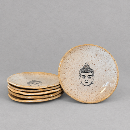 Impish Greetings handcrafted ceramic mini plates with speckled glaze and black Buddha face illustration