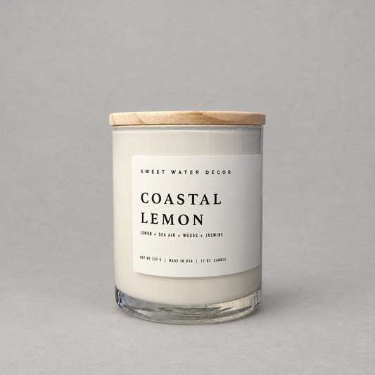 Impish Greetings Coastal Lemon 11 oz soy candle in a glass jar with a wooden lid against a grey background.