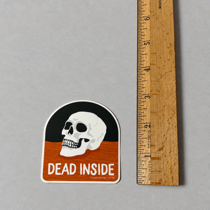 Impish Greetings Dead Inside sticker featuring a skull illustration on a black and orange background with a ruler