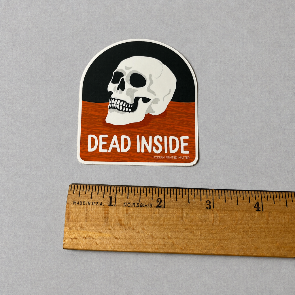 Impish Greetings Dead Inside sticker featuring a white skull on a black and orange background with a wooden ruler