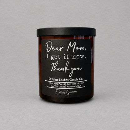 Impish Greetings Dear Mom I get it now soy wax candle in an amber glass jar with a black lid and Endless Summer scent