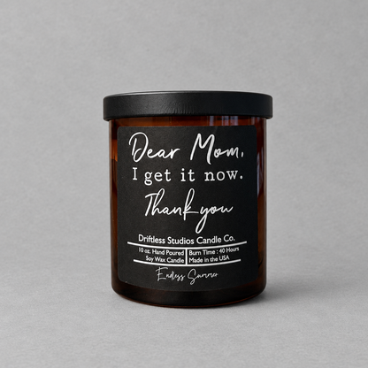Impish Greetings Dear Mom I Get It Now soy wax candle in an amber glass jar with a black lid and minimalist label.
