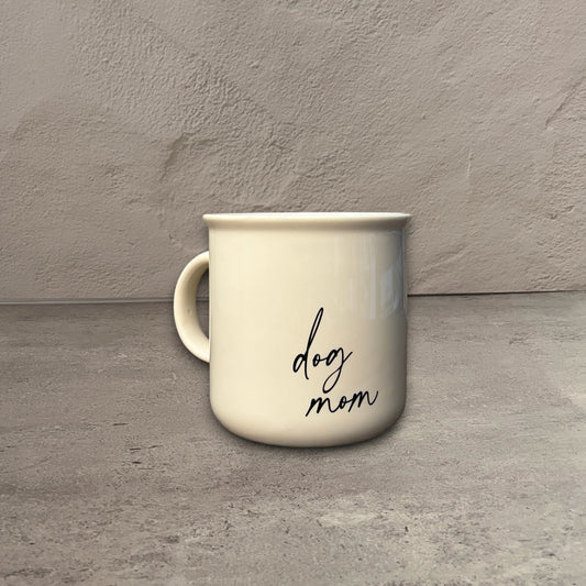 1 oz cream ceramic campfire mug with black cursive dog mom text on a rustic wooden table