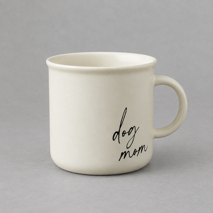 Impish Greetings cream ceramic coffee mug with black cursive dog mom text on a grey background