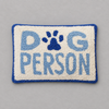 Impish Greetings Dog Person rectangular hook pillow with cream wool front, blue text, and a blue paw print design.