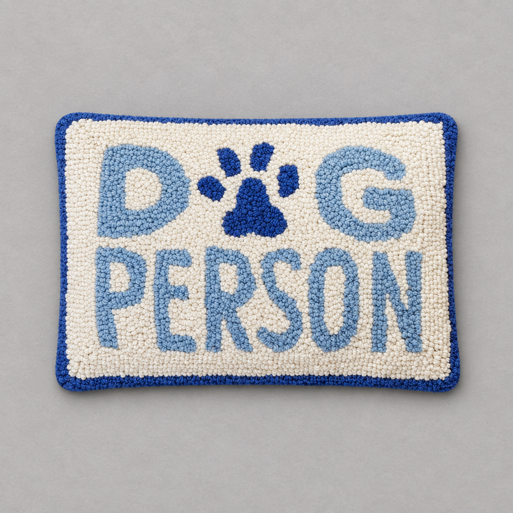 Impish Greetings Dog Person rectangular hook pillow with cream wool front, blue text, and a blue paw print design.
