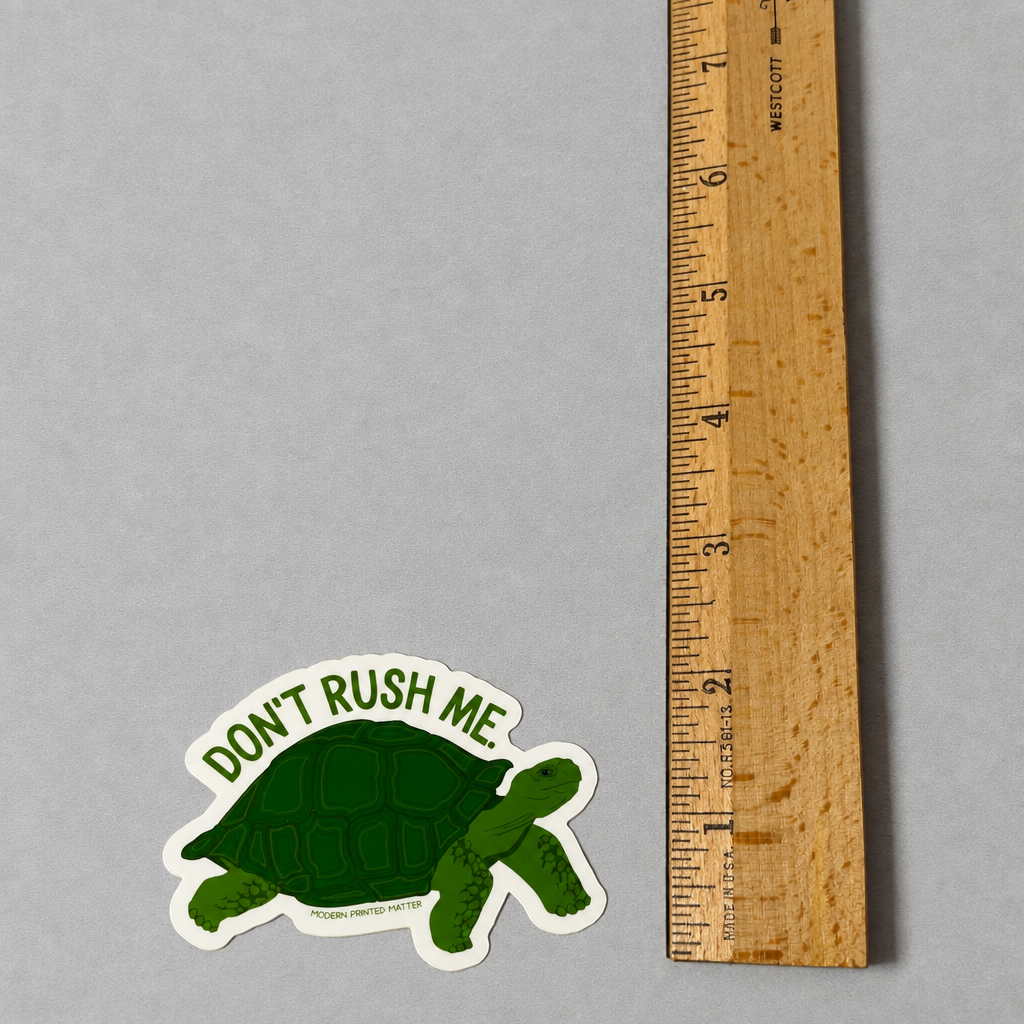 Impish Greetings Don't Rush Me sticker featuring a green turtle illustration next to a wooden ruler for scale