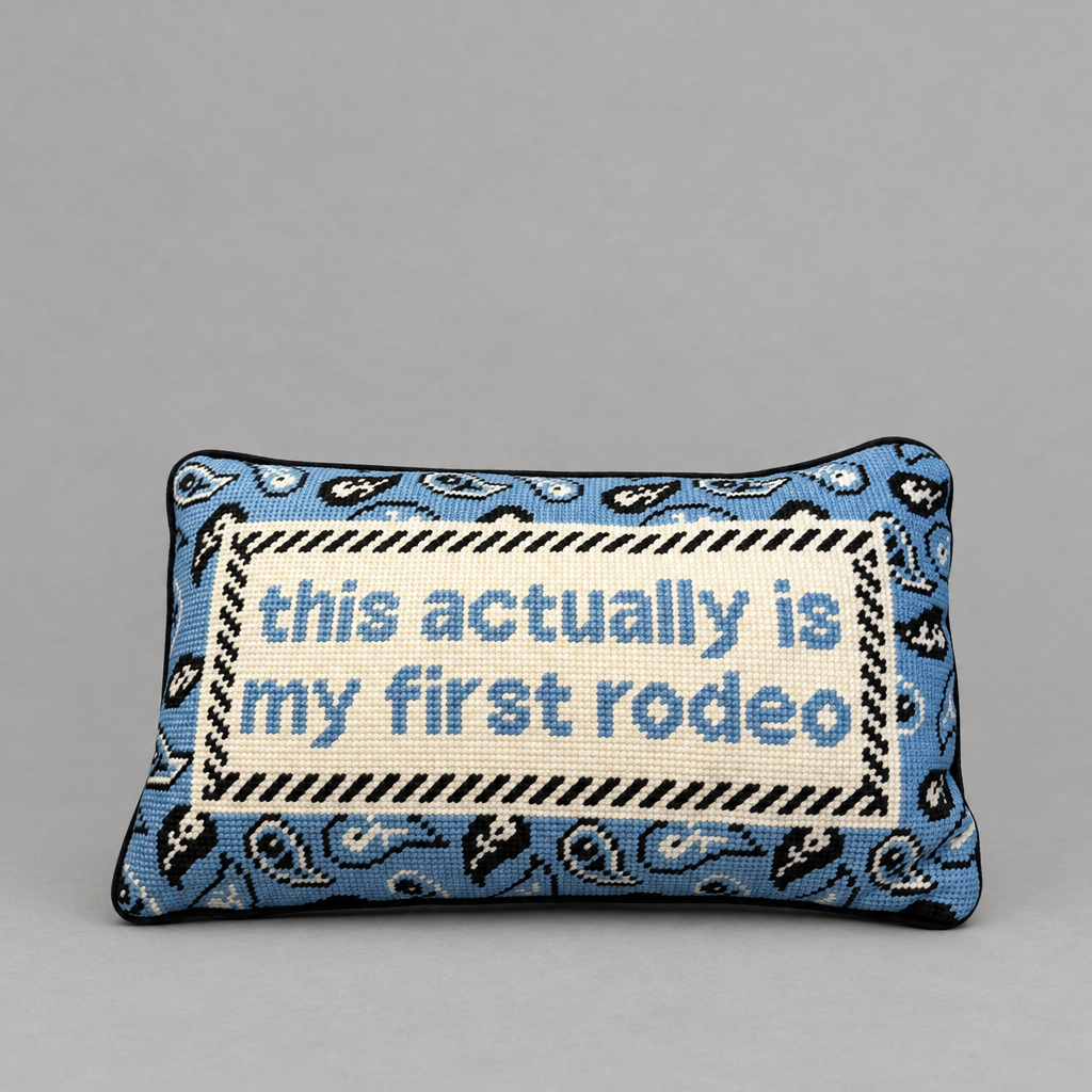 Impish Greetings First Rodeo needlepoint pillow with blue paisley pattern and witty text on a grey background