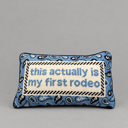 Impish Greetings First Rodeo needlepoint pillow with blue paisley pattern and witty text on a grey background