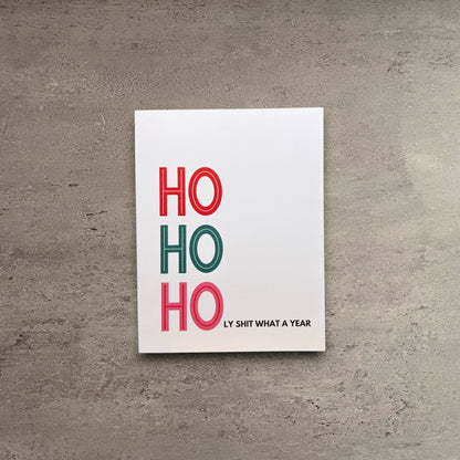Ho Ho Holy Shit What A Year Christmas card on white cardstock with a kraft brown envelope.