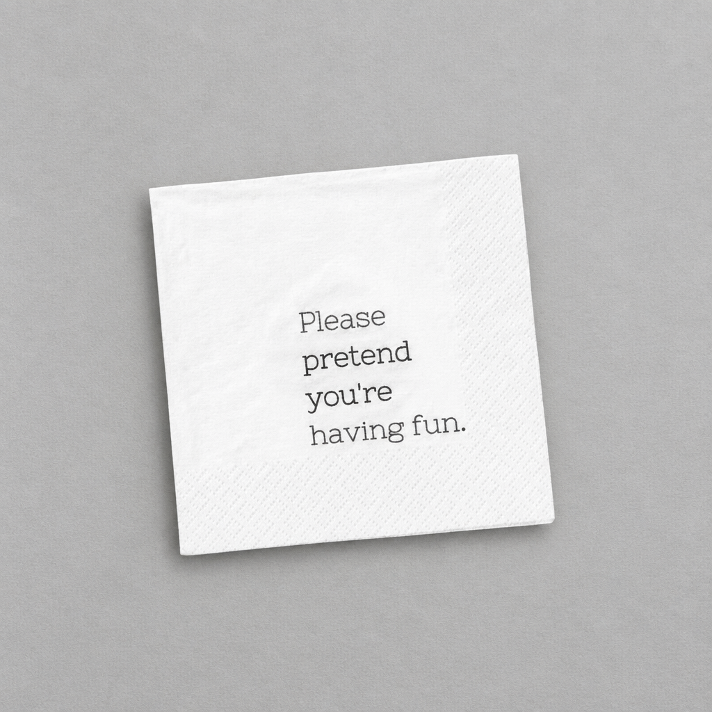 Impish Greetings white 3-ply cocktail napkin with the text Please pretend you're having fun printed in black.