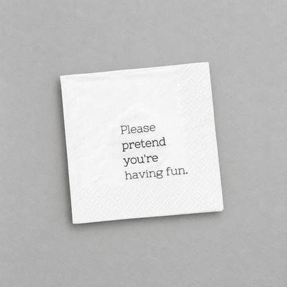 Impish Greetings white 3-ply cocktail napkin with the text Please pretend you're having fun printed in black.