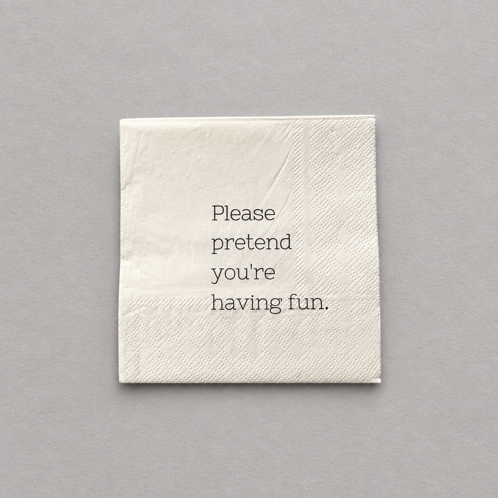 Impish Greetings cocktail napkin in cream 3-ply paper with the text Please pretend you're having fun printed in black