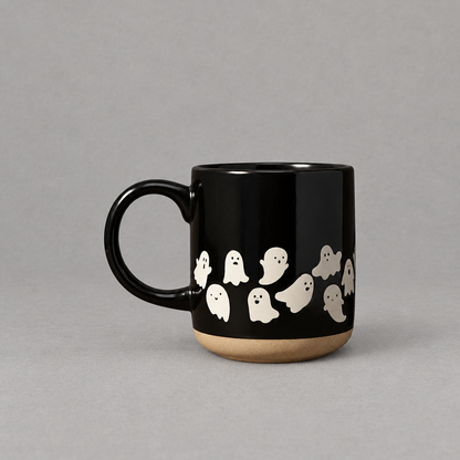 Impish Greetings black stoneware coffee mug featuring a white ghost pattern and a natural clay base.