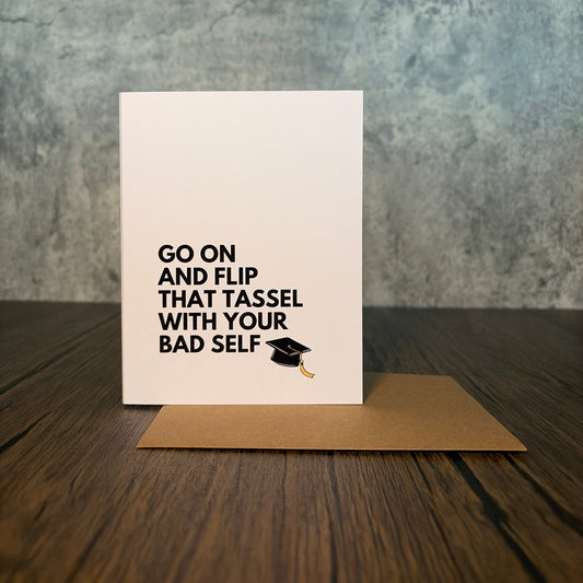 Impish Greetings graduation card with black text and a graduation cap icon, paired with a kraft brown envelope.