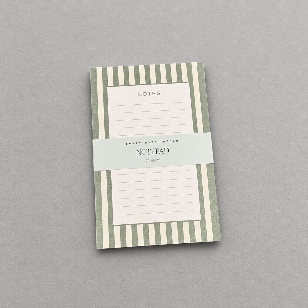 Impish Greetings green striped notepad with 75 lined tear-away pages for notes and to-do lists on a grey background.
