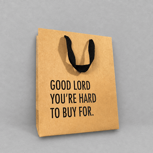 Impish Greetings kraft paper gift bag with black cloth handles and the text Good Lord You're Hard To Buy For.