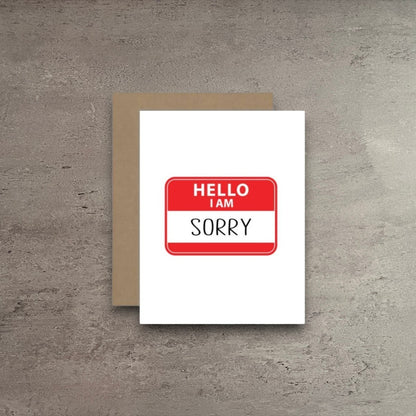 Impish Greetings apology greeting card featuring a red and white Hello I Am Sorry name tag design on white cardstock