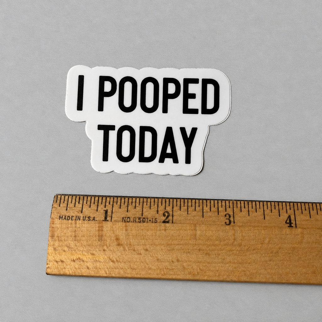 Impish Greetings I Pooped Today vinyl sticker with bold black text on a white background next to a wooden ruler.