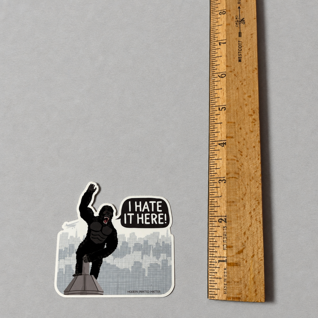 Impish Greetings I Hate It Here sticker featuring King Kong on a building with a speech bubble on a grey background.