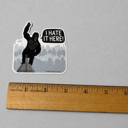 Impish Greetings I Hate It Here sticker featuring King Kong on a skyscraper with a speech bubble on glossy vinyl