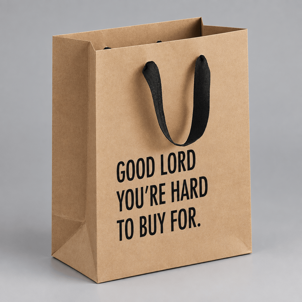 Impish Greetings kraft paper gift bag with black cloth handles and the text Good Lord You're Hard To Buy For.