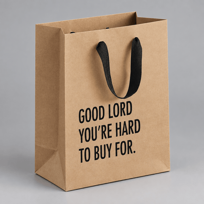 Impish Greetings kraft paper gift bag with black cloth handles and the text Good Lord You're Hard To Buy For.