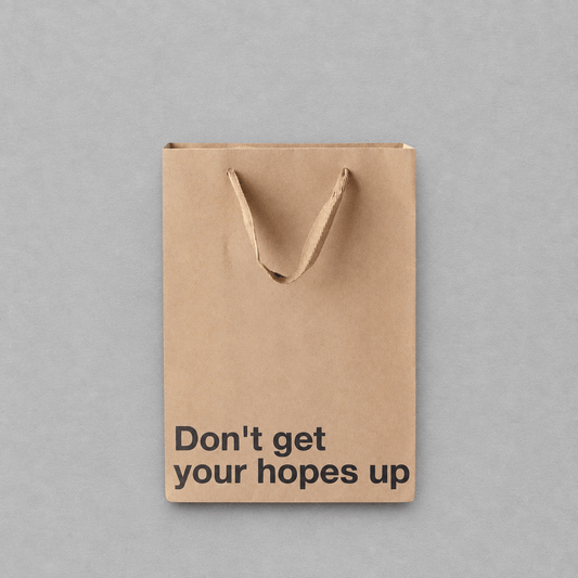 Impish Greetings kraft paper gift bag with the text Don't get your hopes up printed in black on the front.