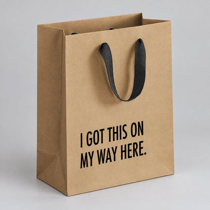 Impish Greetings kraft paper gift bag with black cloth handles and I Got This on my Way Here text in black print.