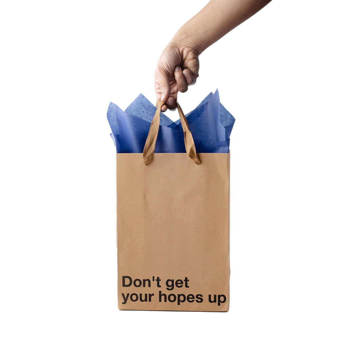 Impish Greetings kraft paper gift bag with blue tissue paper and the text Don't get your hopes up held by a hand